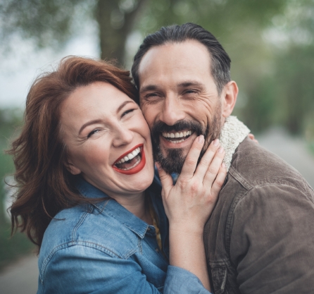 Smiling older man and woman holding each other outdoors