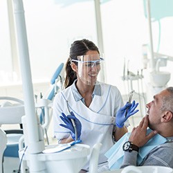 Smiling dentist talking to patient in treatment chair