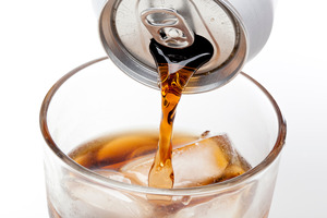 Pouring a diet soda into a glass filled with ice