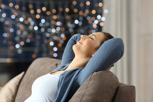 Woman resting on couch with Christmas tree in background